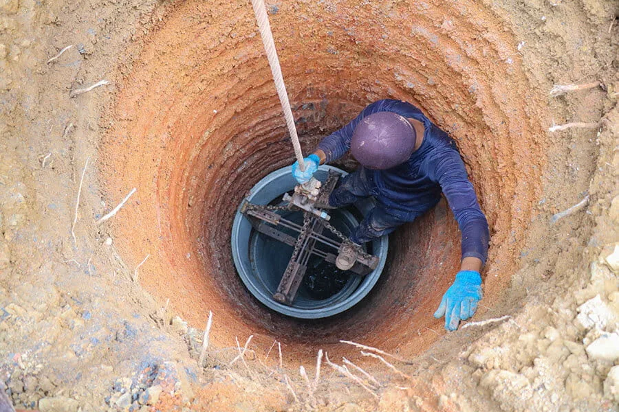 Worker inspecting a borehole well shaft